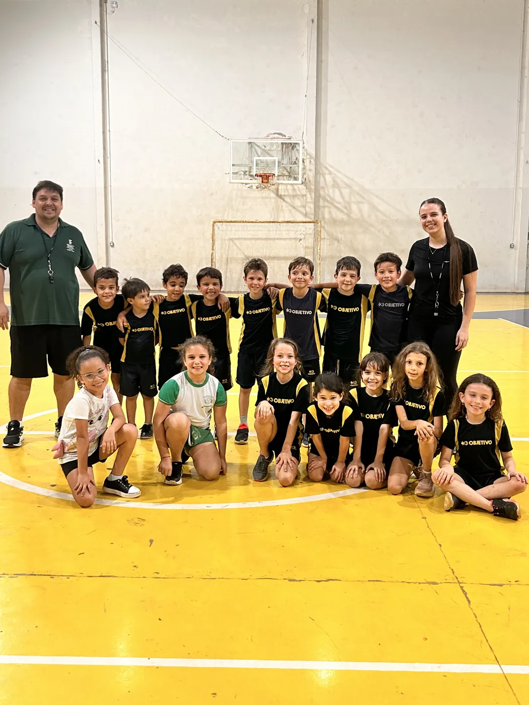 Equipe de alunos posando com os professores na quadra